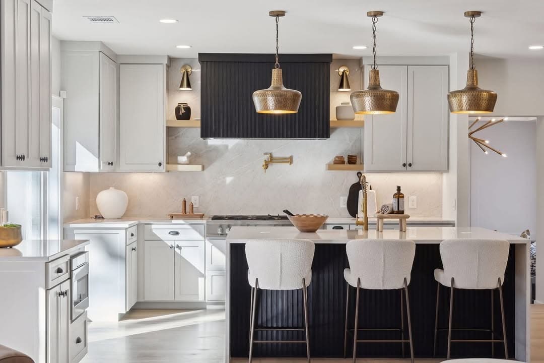 The range wall at 13739 Hughes Lane, a black fluted hood against a marble slab with a pot filler beside it and three stools at the island.