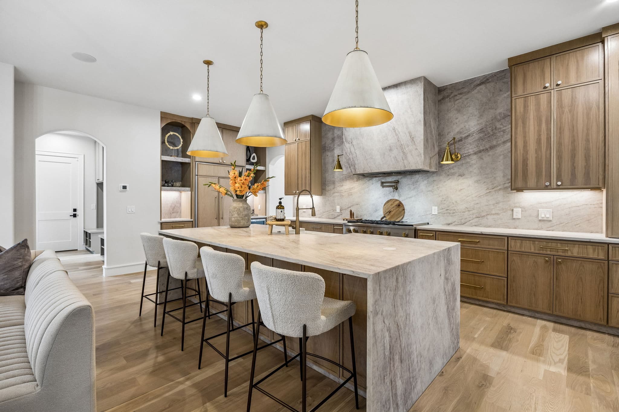 Kitchen at 7272 Tangleglen, a stone island under brass pendants beside oak cabinetry.