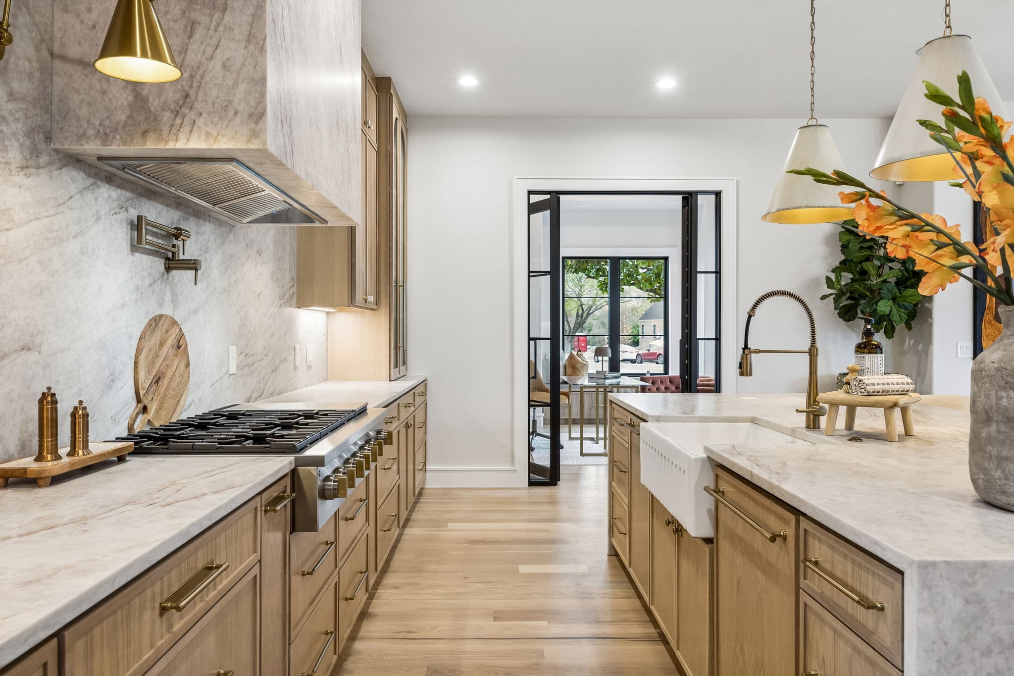 The range at 7272 Tangleglen, a plaster hood over the cooktop with a marble slab behind it and flowers on the counter.