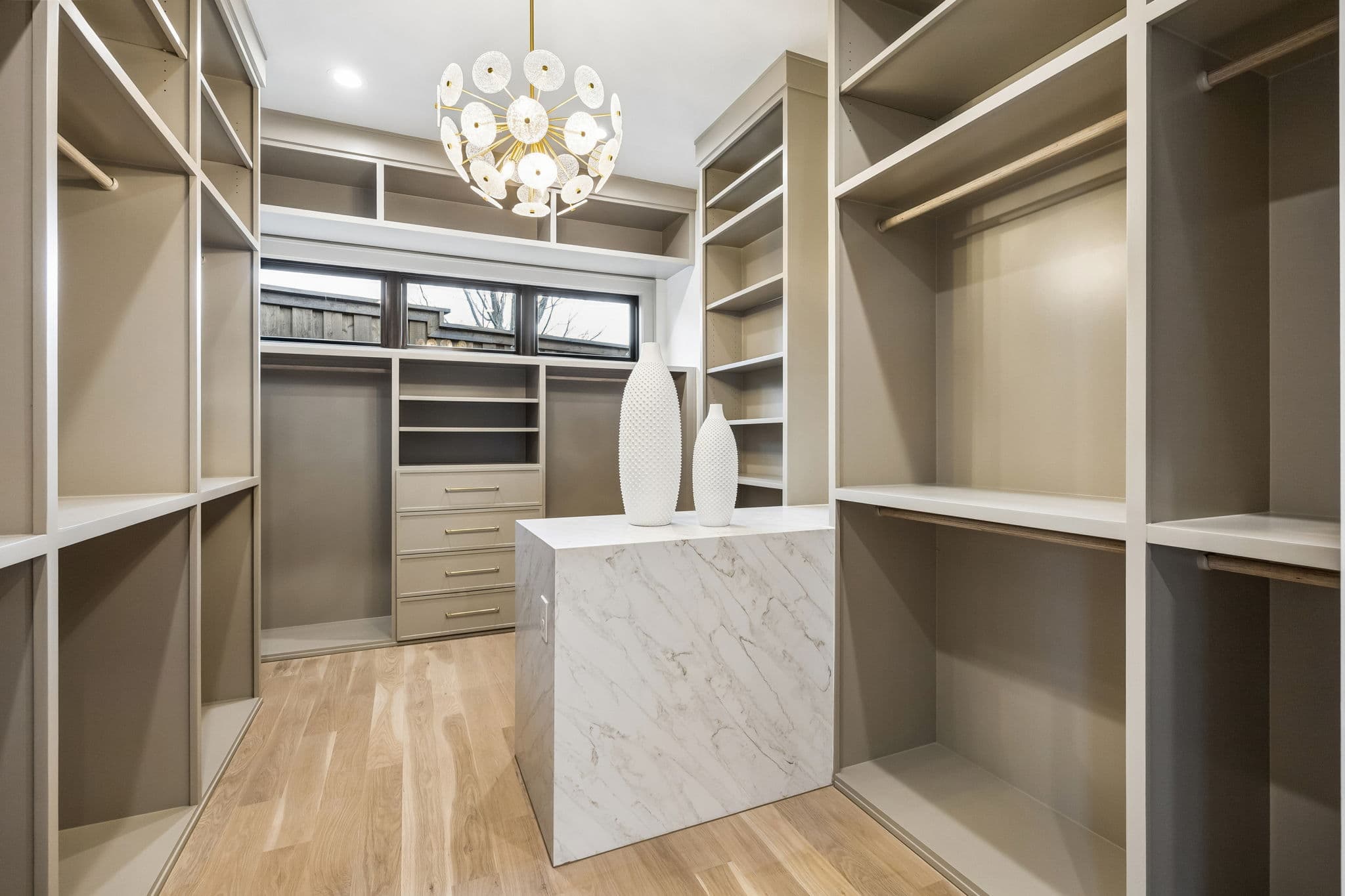 The dressing room at 7272 Tangleglen, open shelving around a stone topped island under a chandelier.