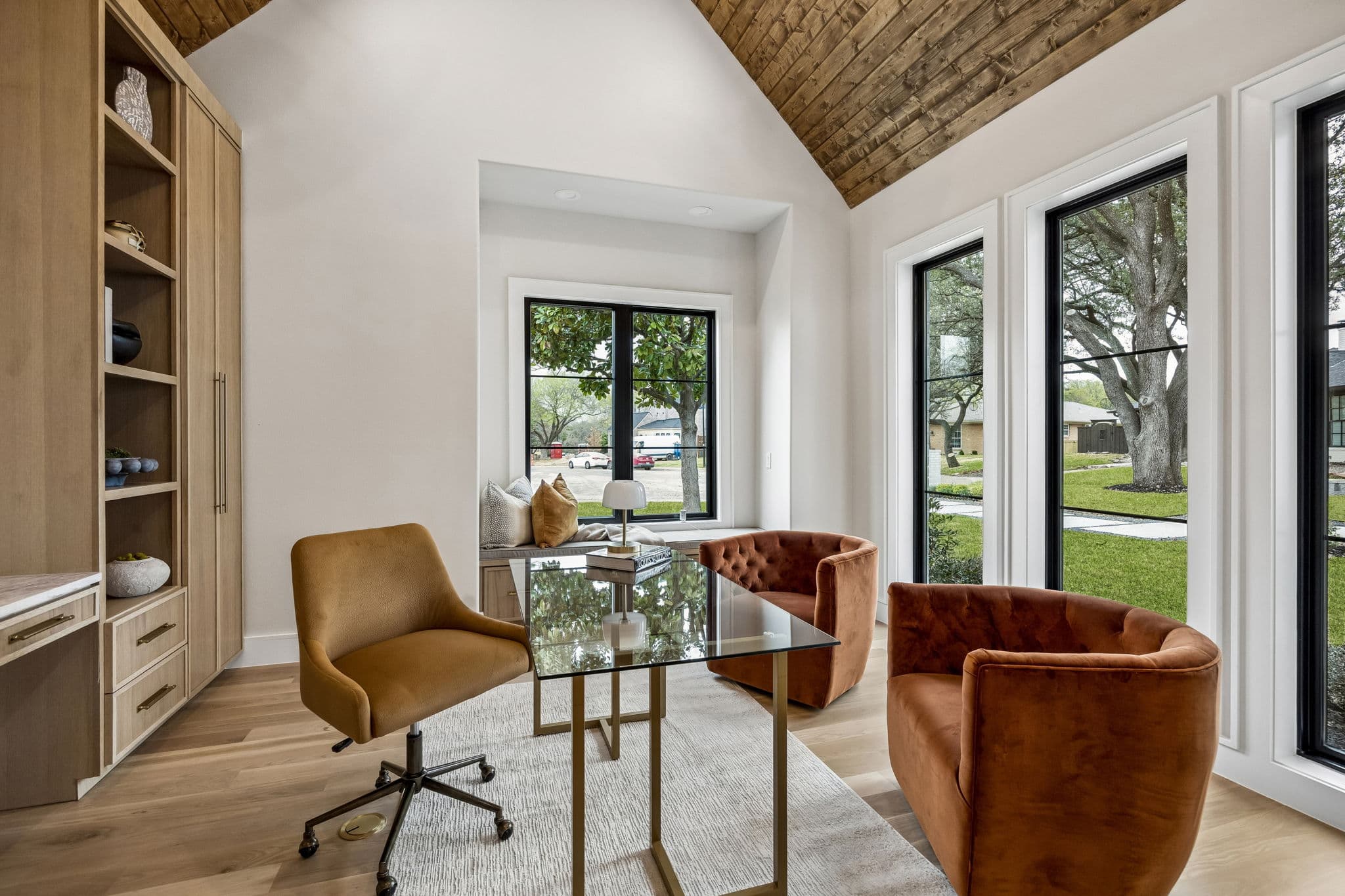 The study at 7272 Tangleglen, two leather chairs under a vaulted ceiling with tall windows onto the garden.