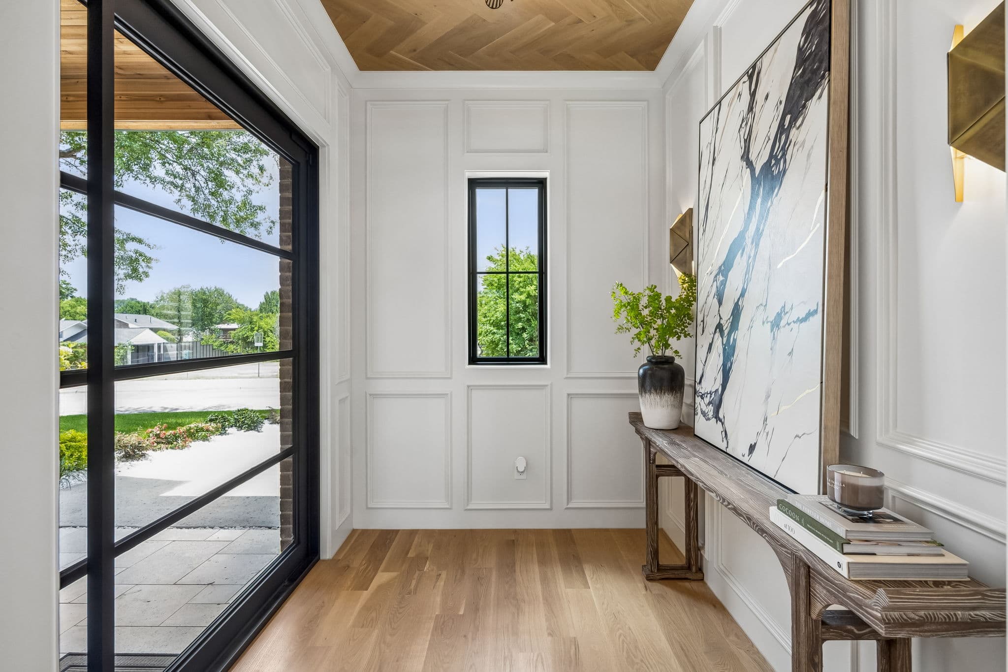 The entry hall at 7308 Tangleglen, oak floors running past a steel door to a console against the panelling.