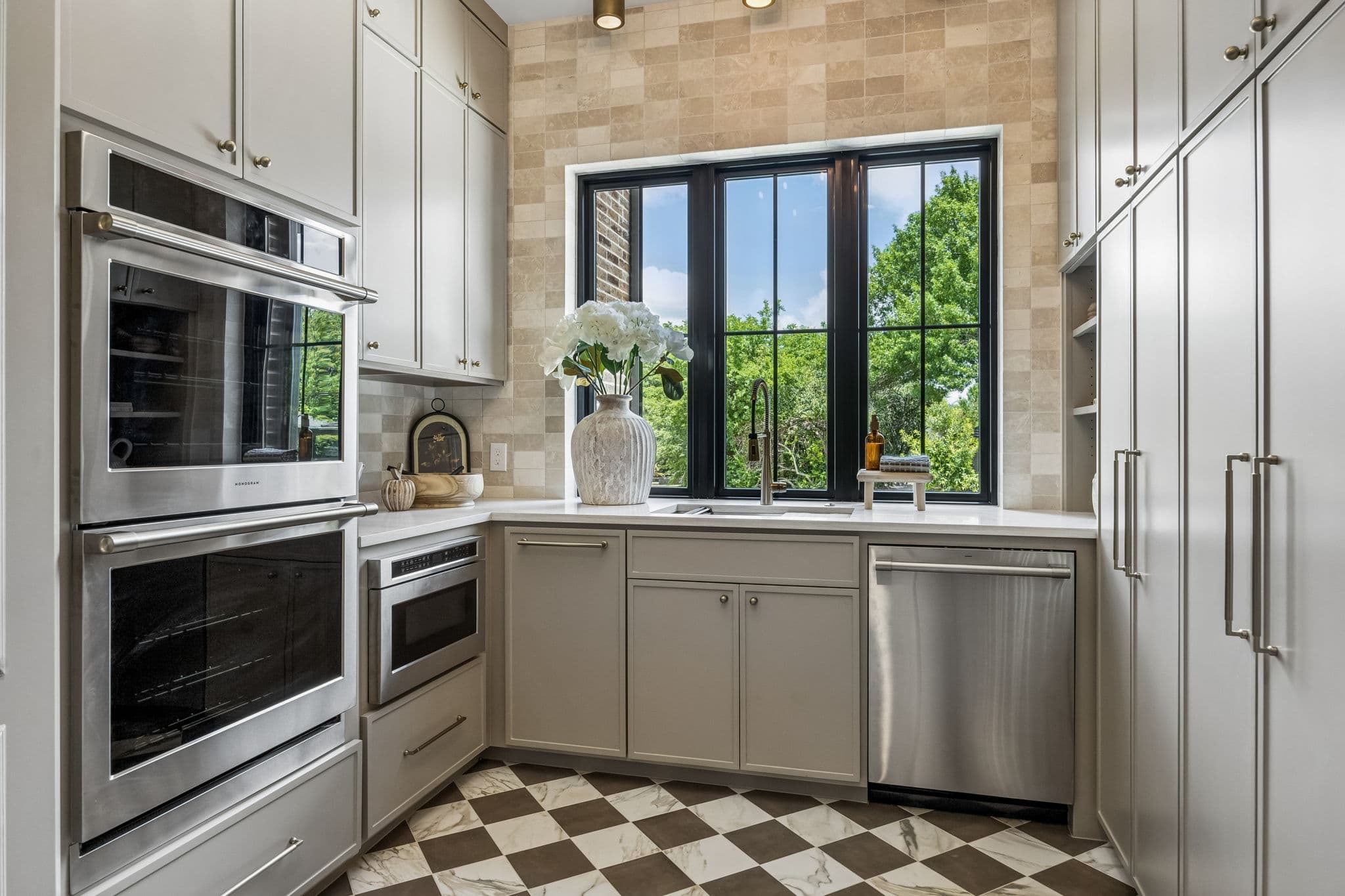 The scullery at 7308 Tangleglen, wall ovens beside a checkerboard floor through the arch.
