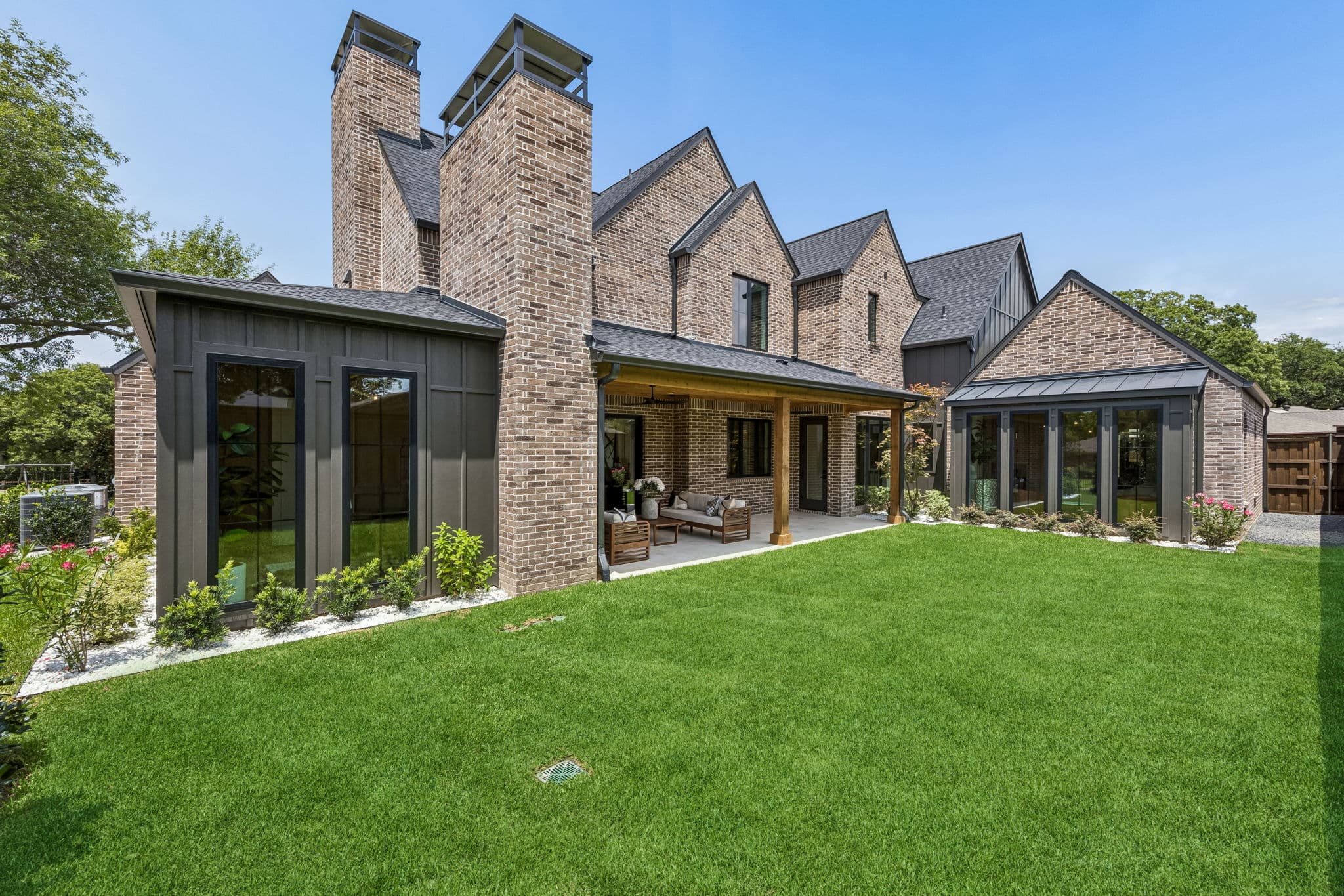 The back of 7308 Tangleglen, twin brick chimneys over a covered porch with lawn across the foreground.
