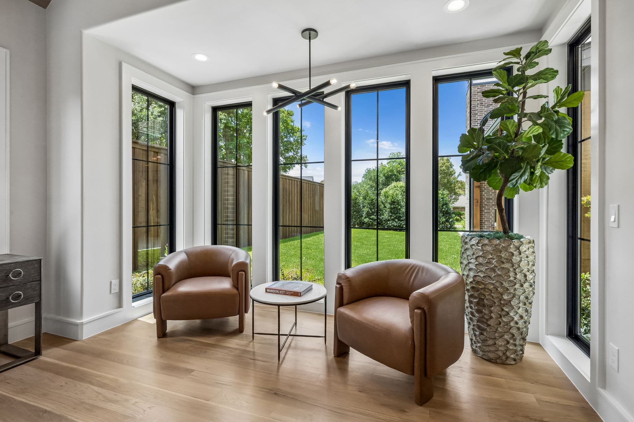The sunroom at 7308 Tangleglen, leather chairs in a bay of windows looking onto the garden.