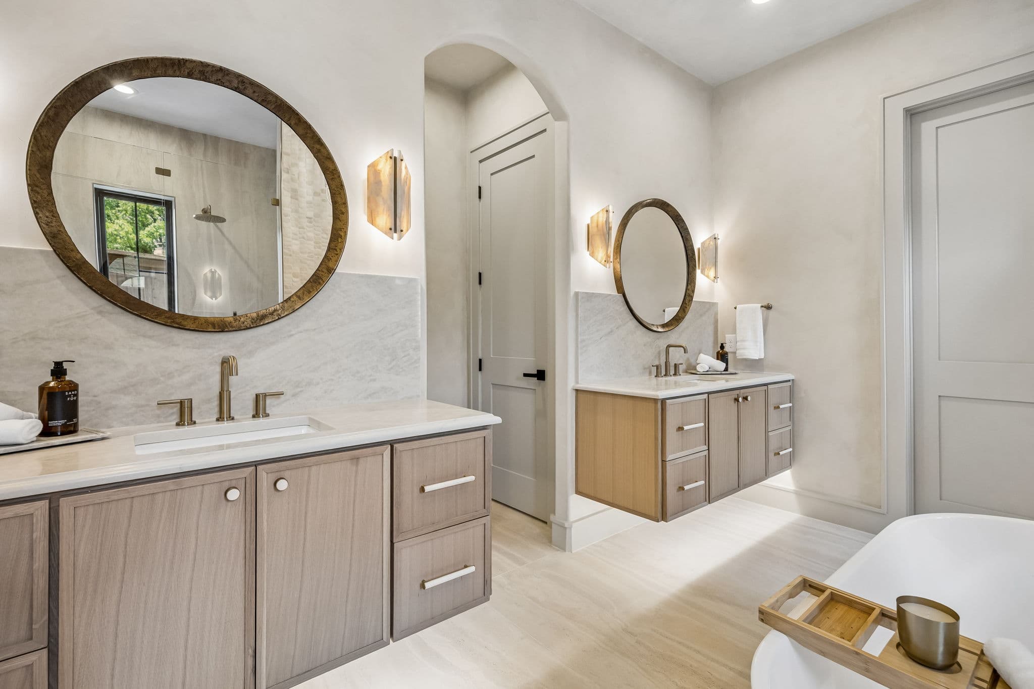 The primary vanity at 7308 Tangleglen, twin basins under round mirrors with a chandelier between them.