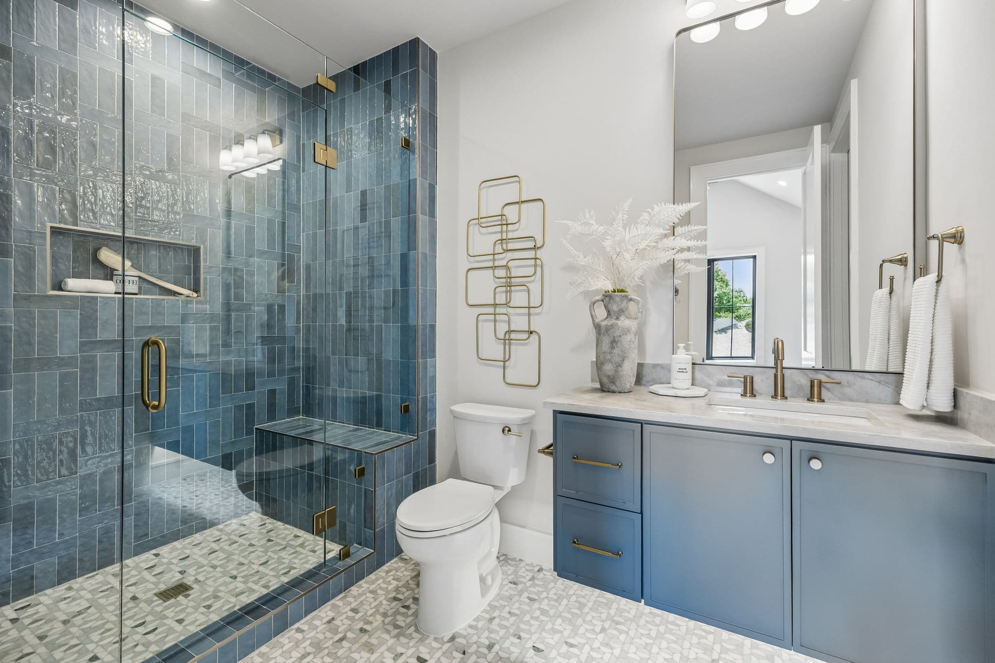 A bath at 7308 Tangleglen, a blue tiled shower beside a blue vanity under a brass mirror.