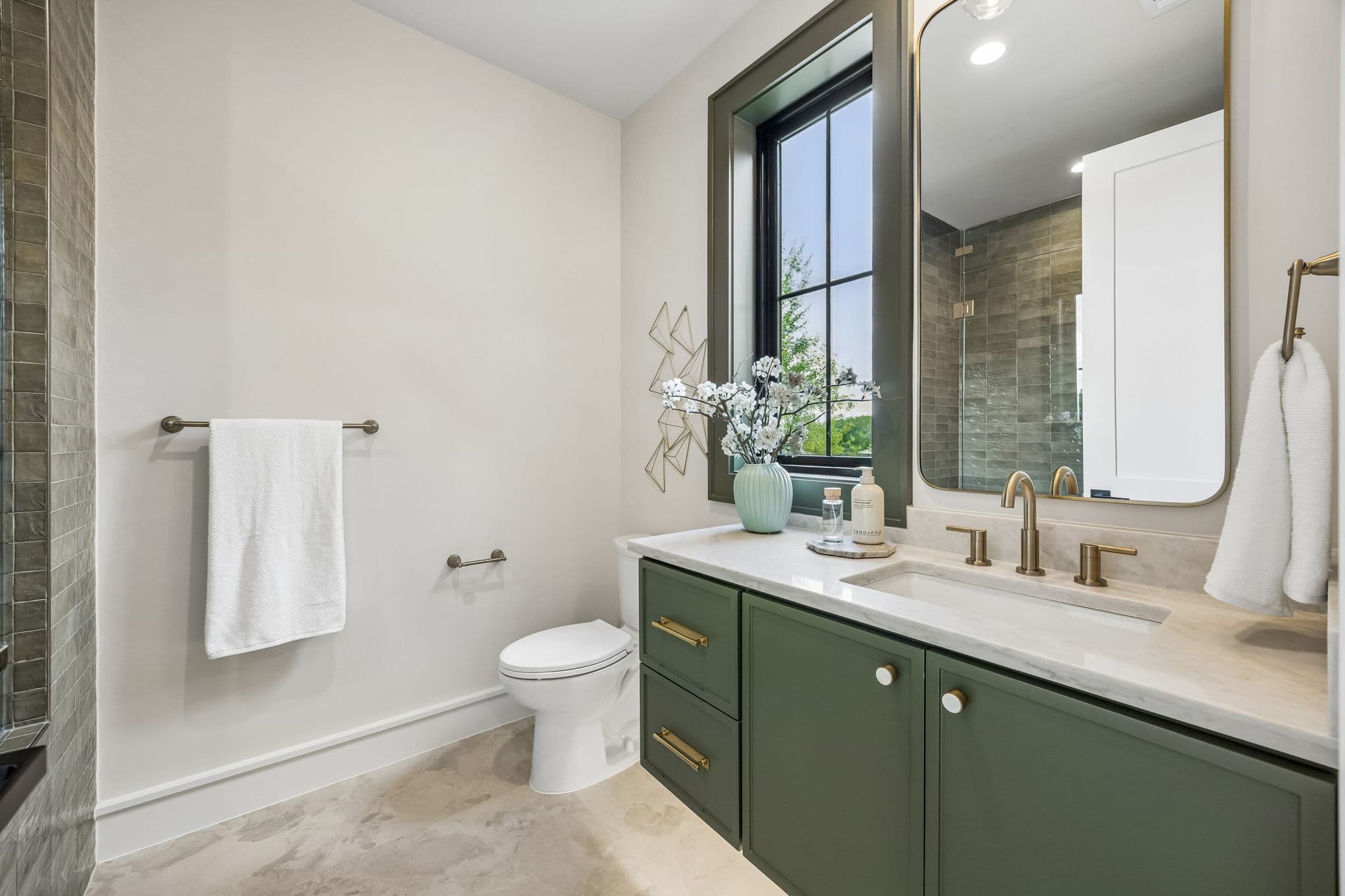 A bath at 7308 Tangleglen, an olive vanity below a slim mirror with a window to one side.