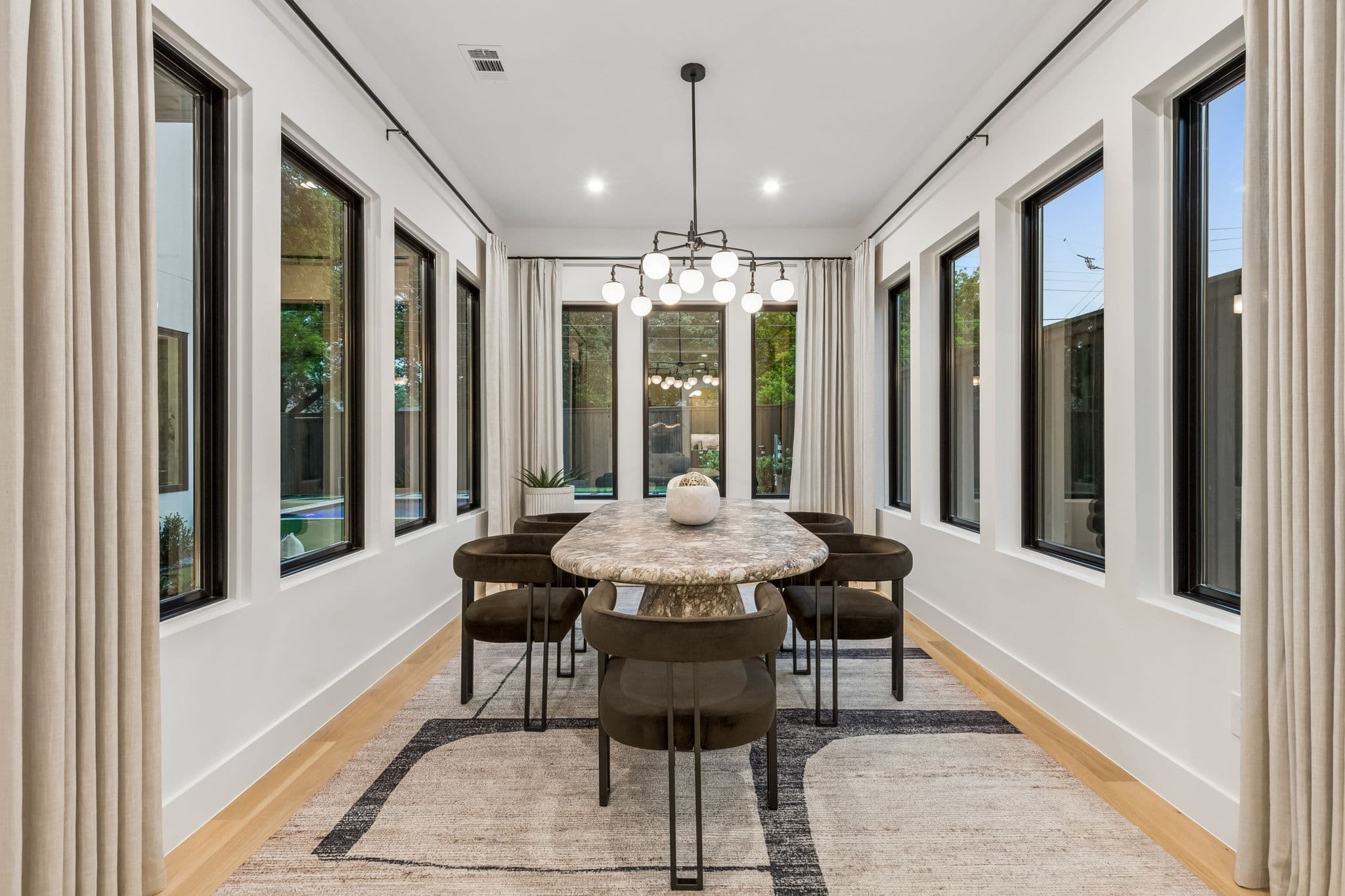 The dining room at 7615 Morton, a table under a chandelier in a bay of windows on three sides.