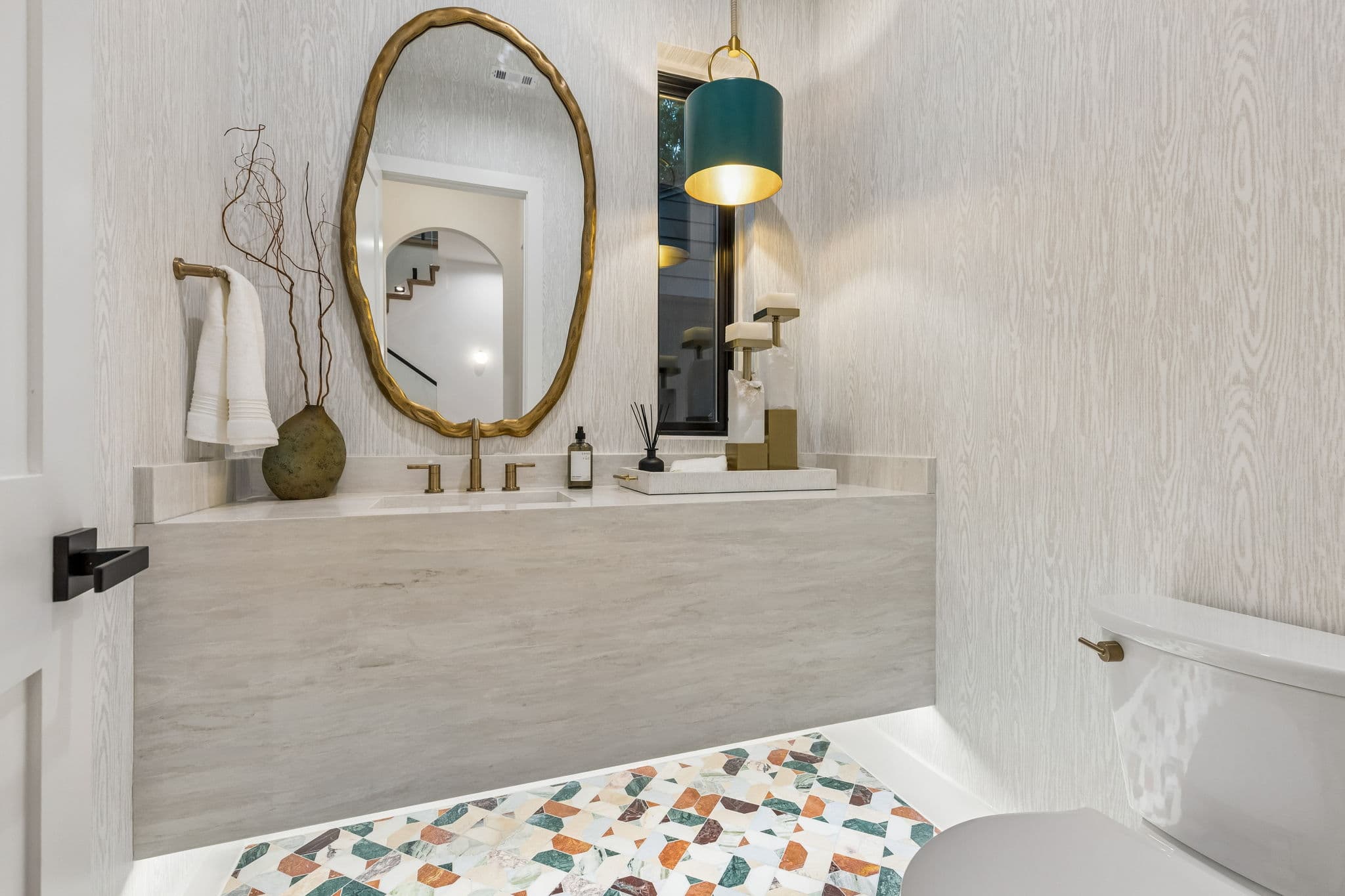 The powder room at 7615 Morton, a gold mirror above a stone counter against a textured wall.