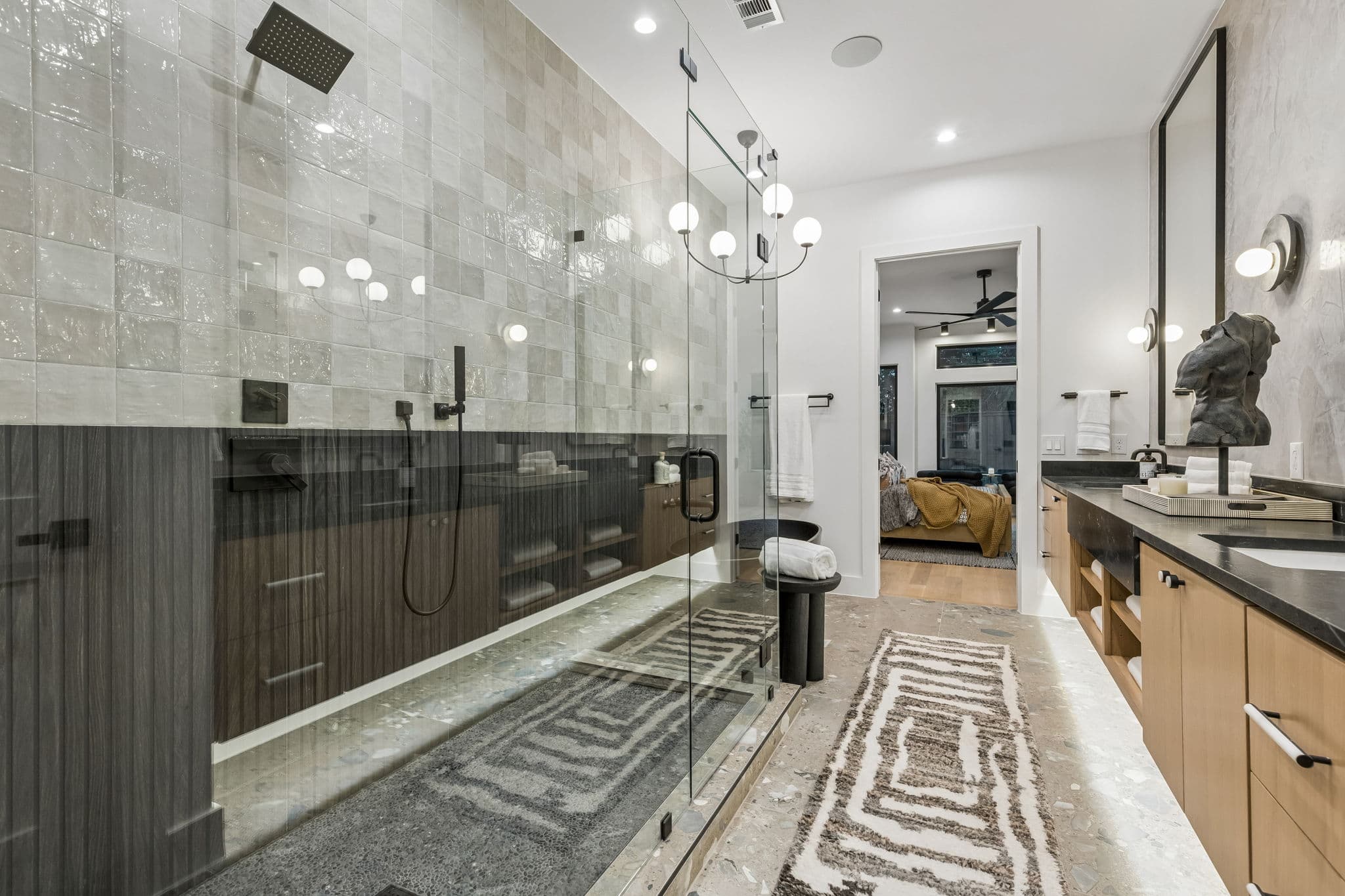The primary shower at 7615 Morton, glass and stone running the length of the wall beside the vanity.