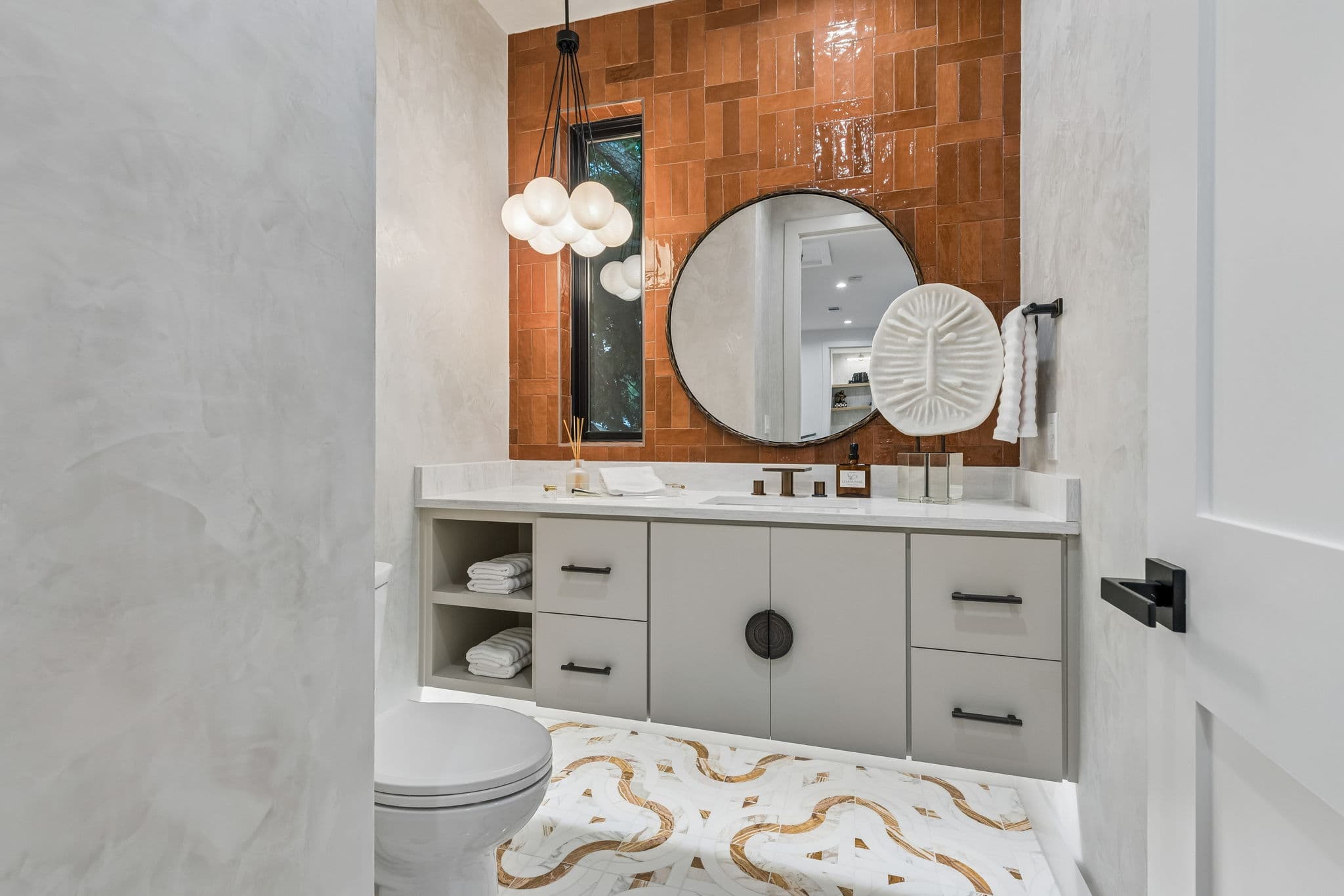 A powder room at 7615 Morton, an arched mirror above a wood vanity with a sconce beside it.
