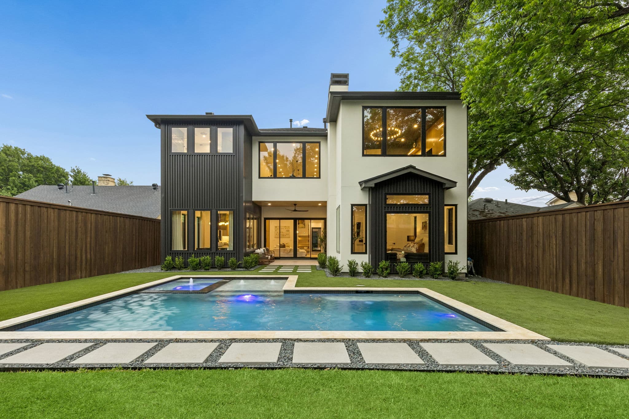 The back of 7615 Morton, the house above a pool with paving set into lawn along the near edge.
