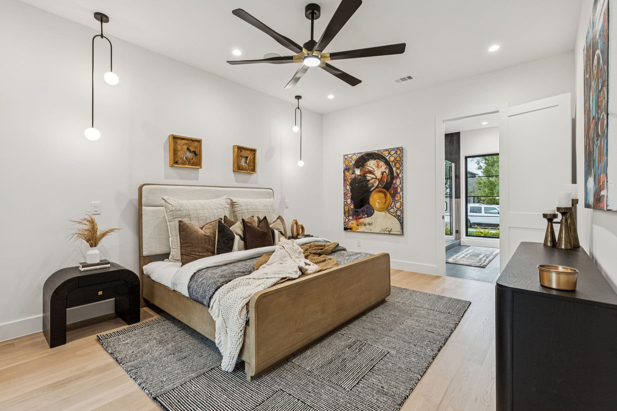 The primary bedroom at 7707 Robin Road, an upholstered bed under a fan with framed pictures behind.