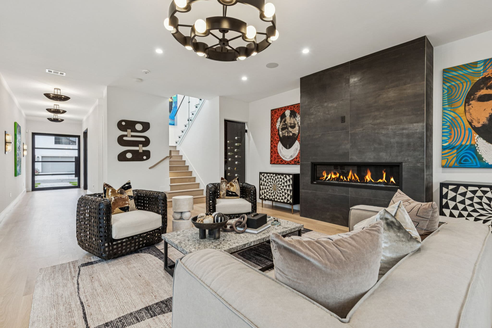 The living room at 7707 Robin Road, a black fireplace between windows with the stair rising behind.
