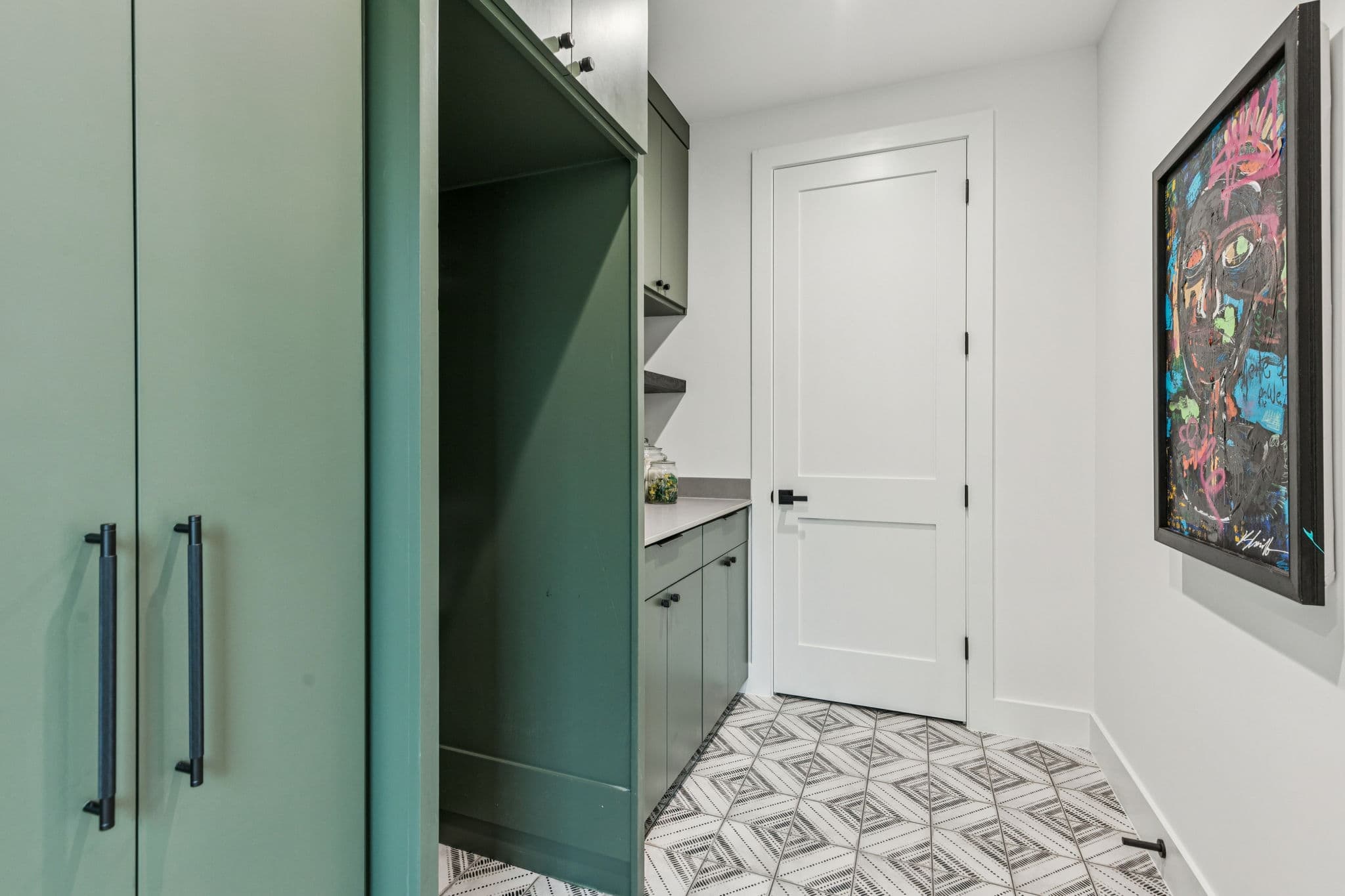 The scullery at 7707 Robin Road, deep green cabinetry above a patterned tile floor.