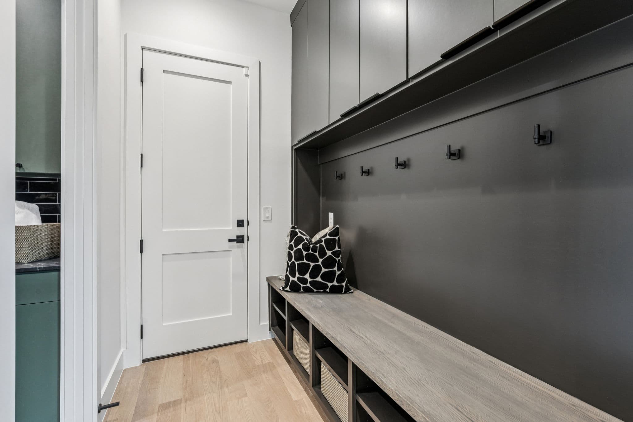 The mudroom at 7707 Robin Road, a bench under a row of hooks against dark panelling.