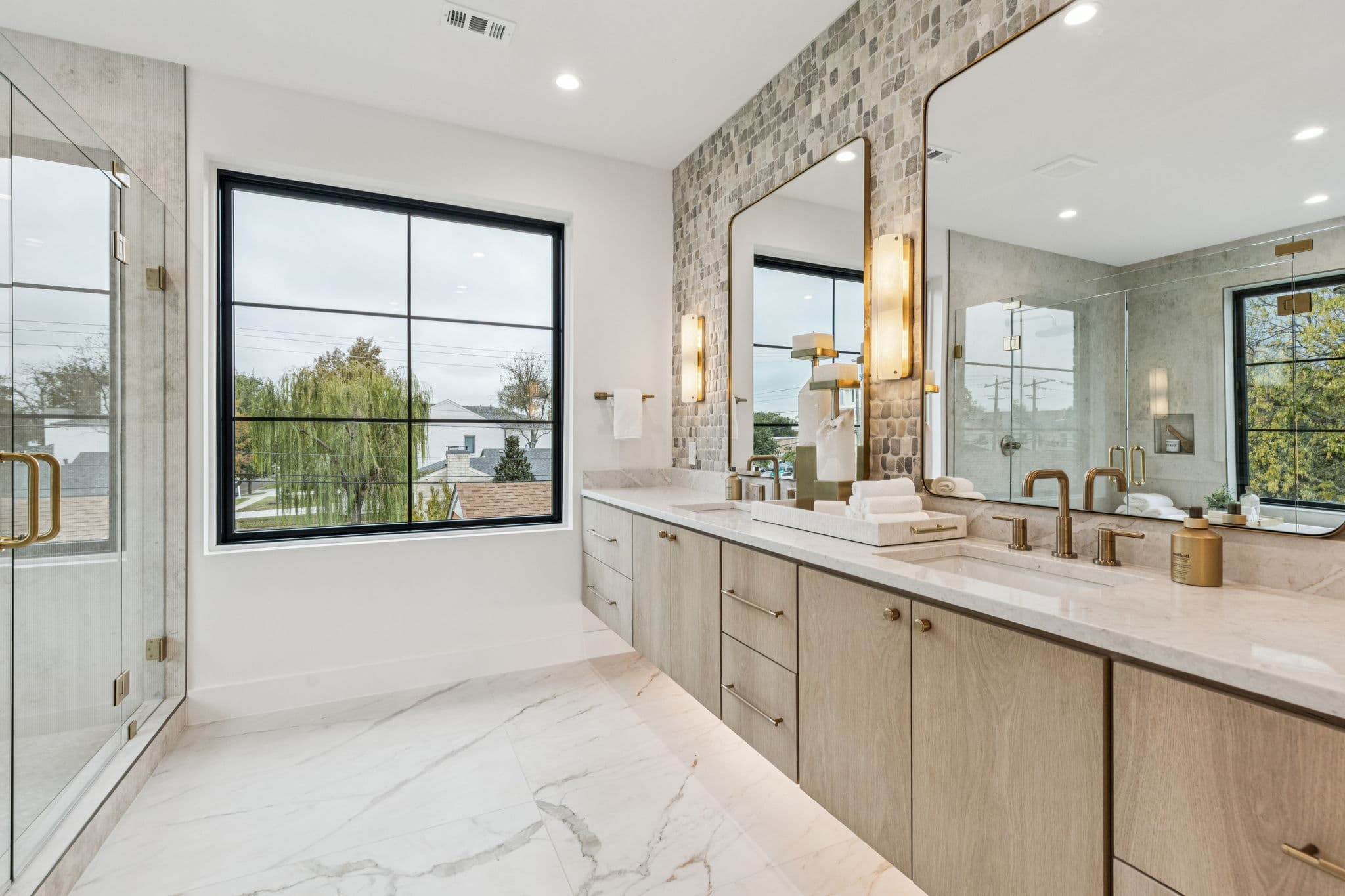 The primary bath at 7707 Robin Road, twin basins under mirrors in a marble lined room.