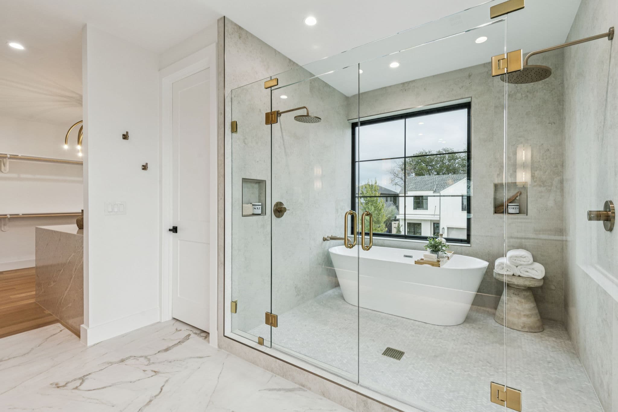 The primary tub at 7707 Robin Road, a freestanding tub beside a glazed shower on marble.