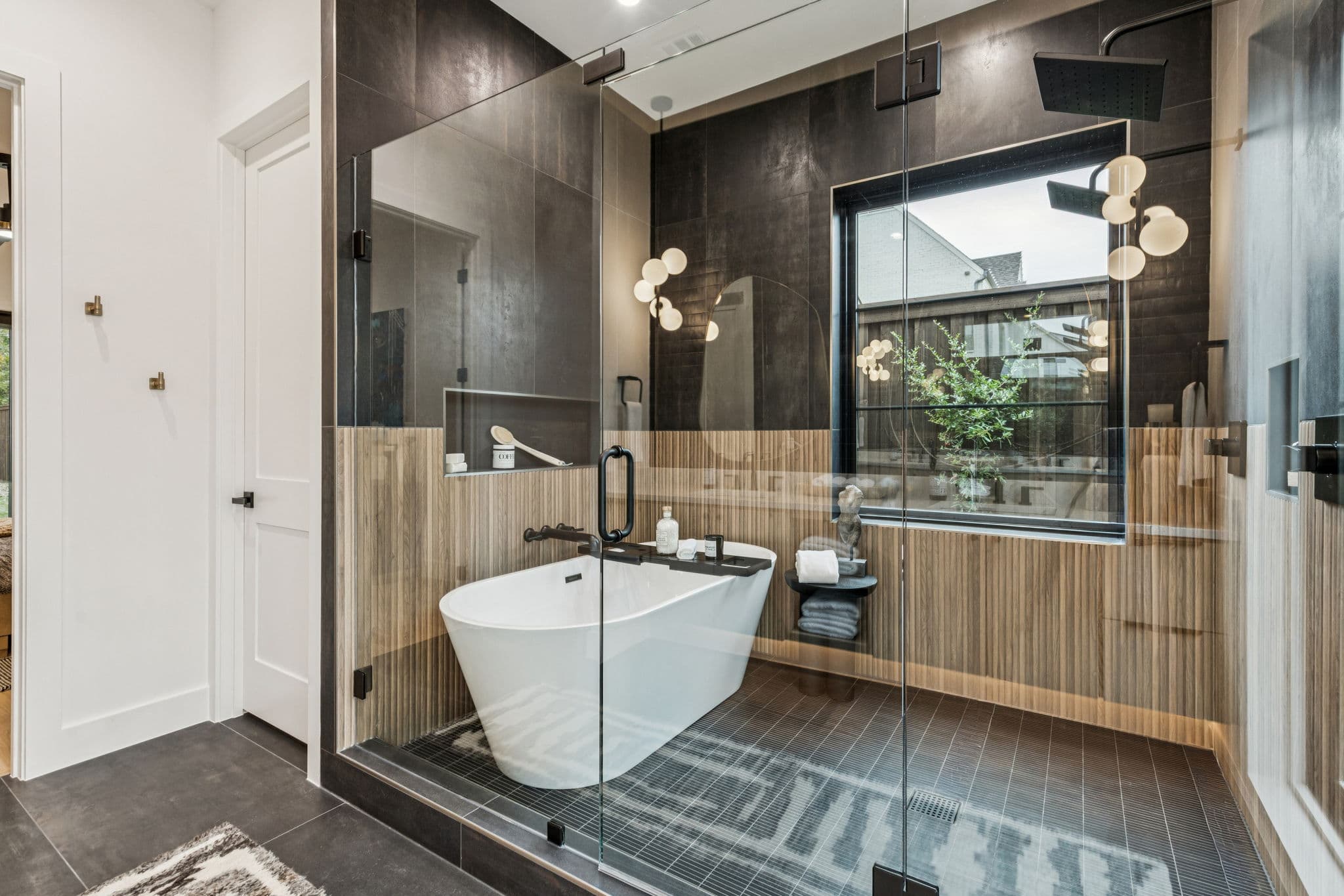 A bath at 7707 Robin Road, a freestanding tub against dark tile below a window.