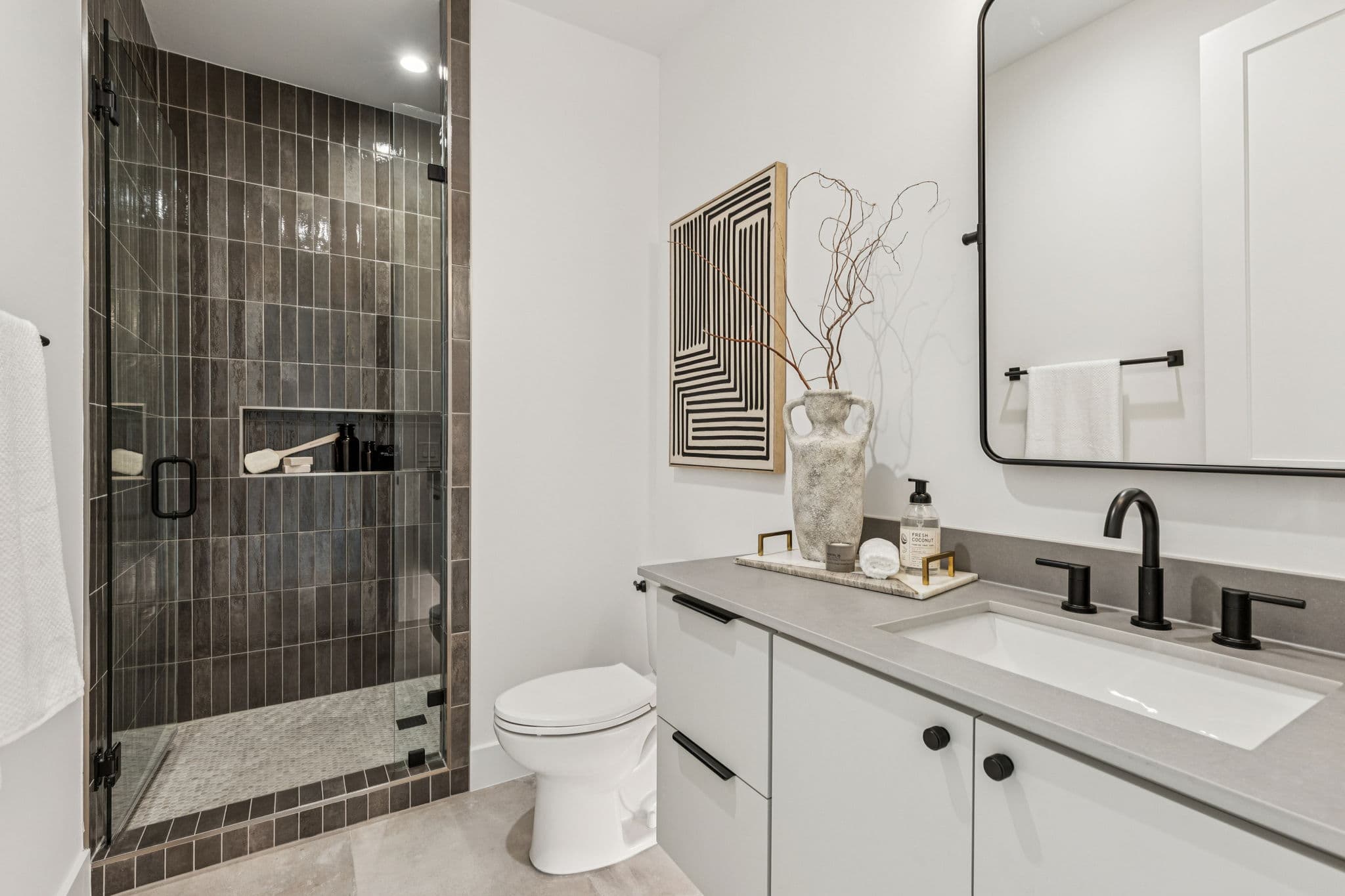 A bath at 7707 Robin Road, a dark tiled shower beside a stone vanity.